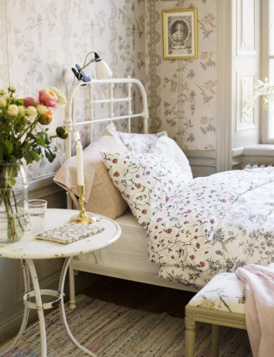 a floral Provence bedroom with floral wallpaper, white metal and wood furniture, floral and pastel textiles, blooms and candles