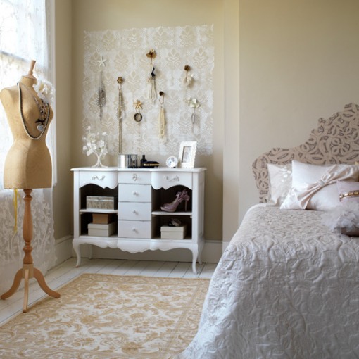 A neutral vintage bedroom with warm colored walls, a pretty patterned bed, a dresser with accessories and a mannequin as decor is very Parisian style