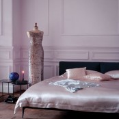 a refined modern bedroom with blush paneled walls, a black bed with blush silk bedding and a mannequin with a refined blush sequin dress
