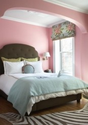 a bright feminine bedroom with pink walls, a green bed in an alcove and vintage curtains and pillows is bold and cool