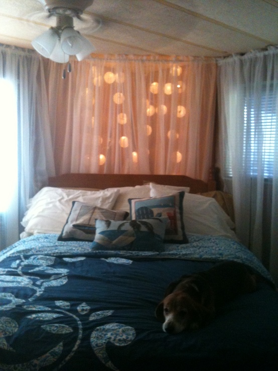 large ball shaped garland with lights hanging over the headboard and covered with a sheer curtain