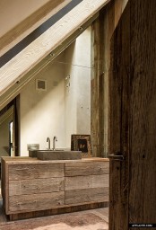 a contemporary barn bathroom clad with reclaimed wood, with a mirror wall and a reclaimed wooden vanity plus a stone sink
