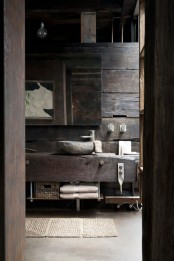 a rough barn bathroom clad with rough reclaimed wood, with a floatign vanity, a large mirror and bulbs