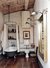 a white barn bathroom with stone walls, a wooden ceiling, wooden planks on the wall and a vintage clawfoot tub with a canopy
