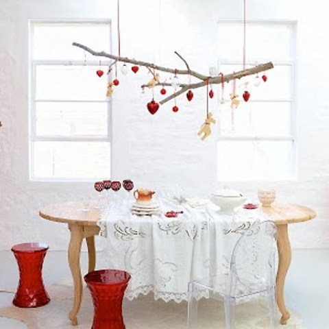 a branch with red and gold Christmas ornaments, red stools and gold goblets for a Scandi dining space