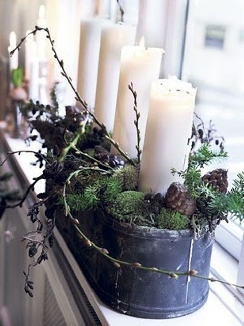 a Scandinavian Christmas decoration of a tin can with moss, branches and candles plus pinecones for a Nordic feel