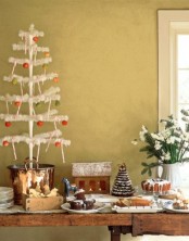 a Scandi Christmas sweets table decorated with a white Christmas tree with colorful ornaments and a white bloom arrangement