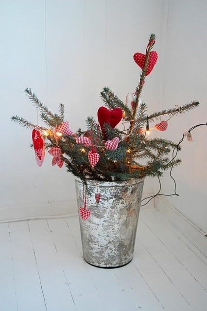 evergreen branches with red hearts and lights in a galvanized bucket for a Scandinavian Christmas feel