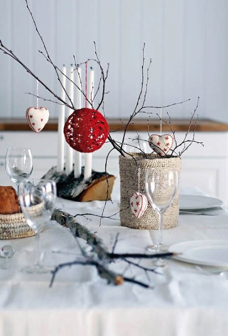 A fun Christmas centerpiece with a burlap wrapped tin can and branches plus a red yarn ball and heart shaped fabric ornaments
