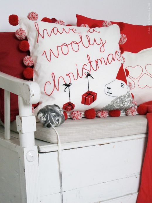 a neutral Christmas bench with white and red pillows with pompoms and a red blanket for Christmas