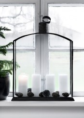 a large black lantern with candles and pinecones is a stylish Nordic decoration