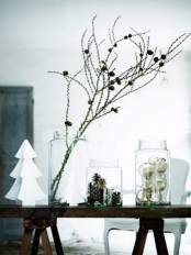 three big glass jars – with pinecones, metallic ornaments and branches with pinecones for a modern Nordic feel