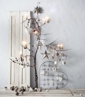 branches with metallic ornaments, pinecones and candles and candles and ornaments under them for a Nordic look