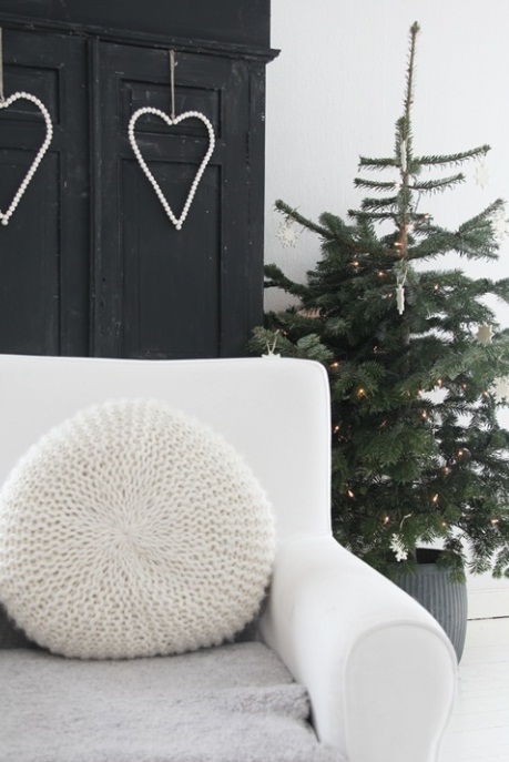 A Christmas tree decorated with lights, white ornaments in a basket looks Scandinavian like