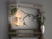 a frame with greenery, branches, metallic ornaments and a candle lantern for a Nordic decoration