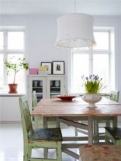 a shabby chic space with a rustic table, green shabby chairs and a pure white backdrop