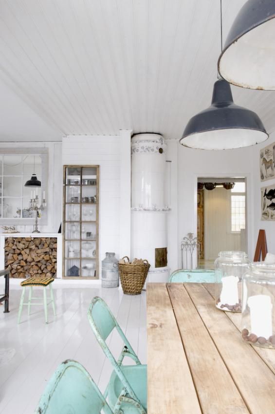 A Nordic kitchen with a wooden table, mint chairs, vintage pendant lamps, a stove and a built in buffet