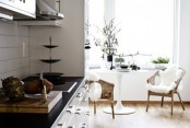 a cozy monochromatic kitchen, a black countertop, wicker chairs, faux fur and a round table