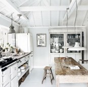 a white Nordic kitchen with a whitewashed buffet, pendant lamps, a rough wooden dining set