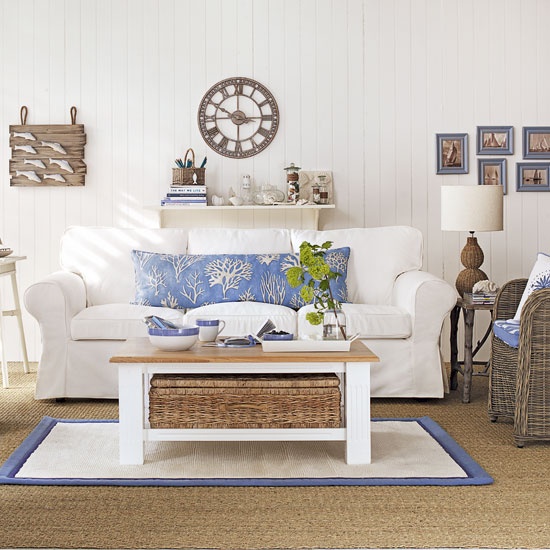 A traditional beach living room with white upholstered and rattan furniture, touches of blue and sea inspried artworks