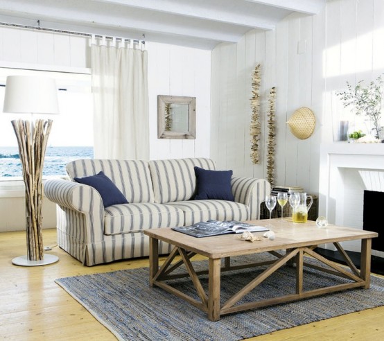 a coastal living room with a view, a striped sofa, a wooden coffee table, strands of seashells and a driftwood lamp