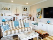 a neutral beachy living room with a striped sofa, a built-in shelving units with items on display and some sea-inspired accessories