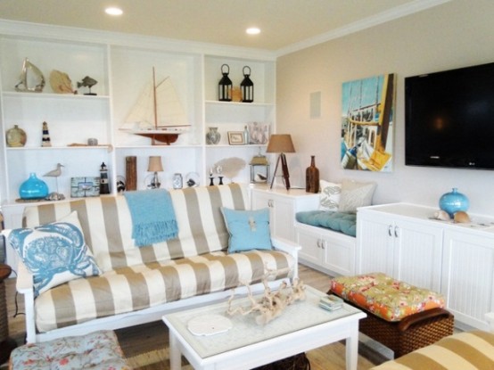 a neutral beachy living room with a striped sofa, a built-in shelving units with items on display and some sea-inspired accessories