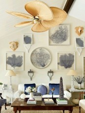 an attic beach living room with a white sofa, blue pillows and a large gallery wall with beautiful art pieces plus a rattan fan