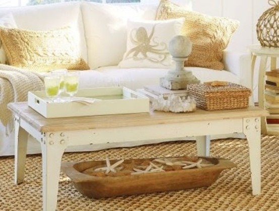 a sunlit beach living room with a wooden coffee table, baskets and a dough bolw plus sea-inspired pillows
