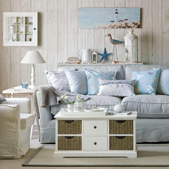 a neutral and powder blue living room with whitewashed wood walls, vintage upholstered furniture and a coffee table with basket drawers