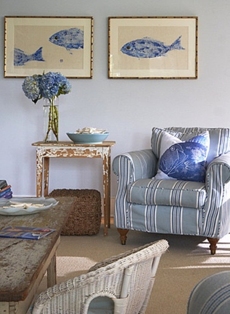 A light blue, grey and tan living room in coastal style with striped and rattan furniture, sea inspired artworks