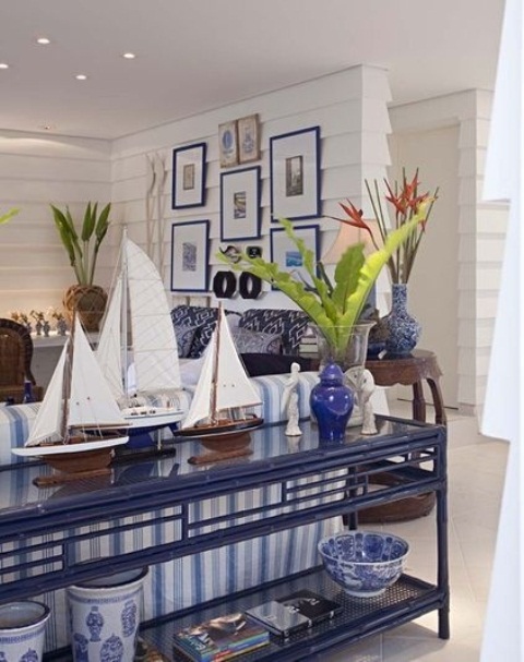 A navy and white coastal living room with a striped sofa, a navy console and a gallery wall with sea inspired artworks