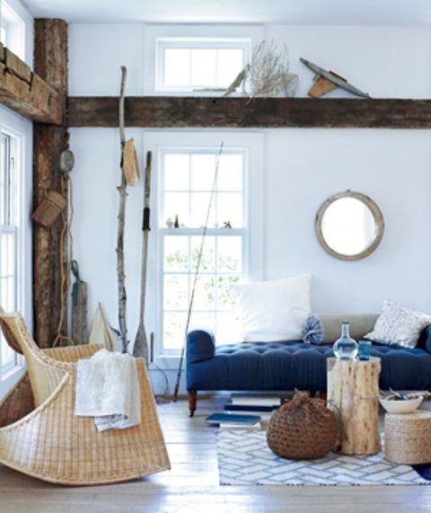 a modern coastal living room in navy, white and tan, with much wood, rattan, wicker and some decorative items