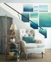 a bold and large sea-inspired gallery wall, a white upholstered chair and an etagere with books and aqua accessories