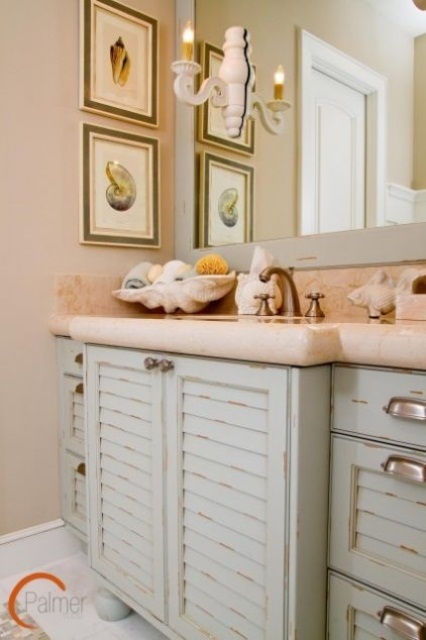 a blush and grey bathroom with a vintage vanity with a pink countertop, sea-inspried artworks and a seashell soap dish