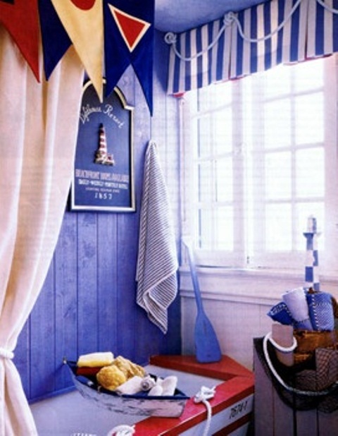 a blue, red and white bathroom with a boat-shaped bathtub, catchy curtains and sponges and towels for a more sea-inspired feel