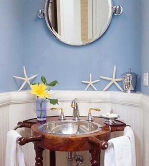 a blue and white vintage bathroom with a round mirror and a stained vanity with a vessel sink