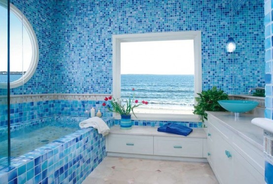 a blue sea-inspired bathroom with mosaic tiles, white furniture and large windows with ocean views