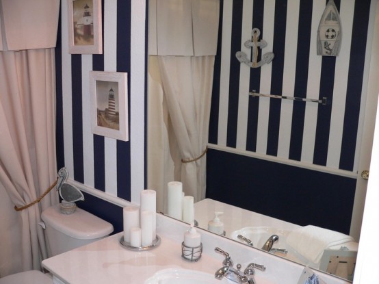 a black and white bathroom with sea-inspired artworks and some appliques on the wall