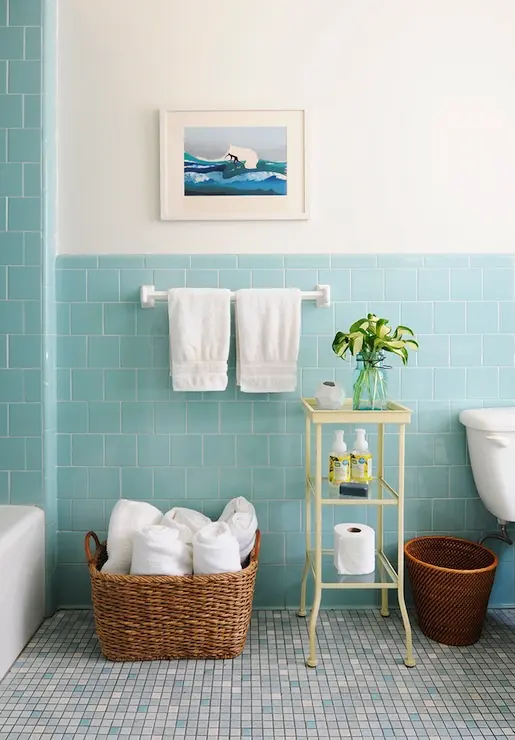 an aqua colored sea bathroom with a mosaic floor, some baskets for storage and a pastel etagere