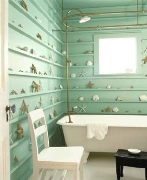 an aqua colored bathroom with lots of ledges along the walls and starfish and seashells plus gold touches