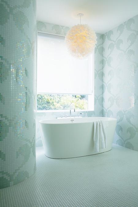 an ocean-inspired bathroom fully clad with aqua-colored mosaic tiles showing off patterns plus a fluffy pendant lamp