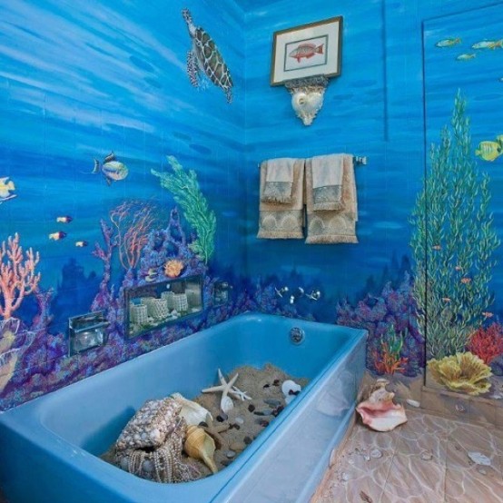 a super bright bathroom with a blue tub with sand and starfish plus seashells and coean-inspried wall murals