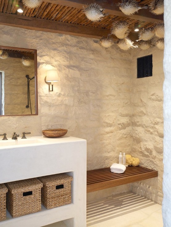 a beach bathroom with stone clad, a white vanity with baskets for storage and faux fish suspended to the ceiling