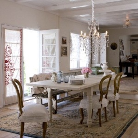 a simple shabby chic dining space done in neutrals, with a vintage crystal chandelier, vintage furniture and a cool rug