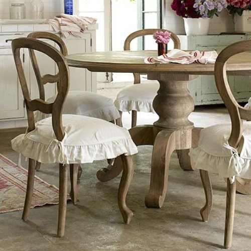 a rustic meets shabby chic dining room with vintage wooden furniture, white ruffle covers and chic white furniture for storage