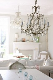 an elegant shabby chic dining room with white furniture, a beautiful chandelier with blue touches and blue floats for a coastal feel