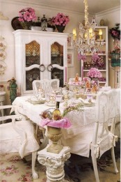a white and pink shabby chic dining room with elegant furniture, a vintage chandelier, blooms in pots and urns