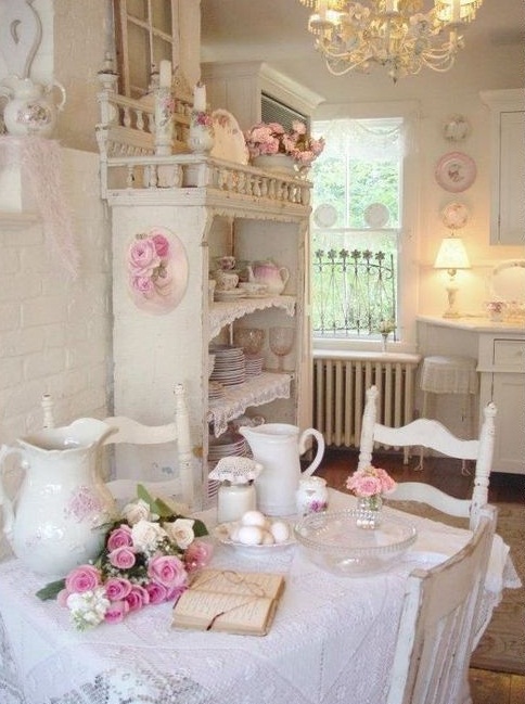 a shabby chic dining room in white with pink touches, with cool shabby chic furniture, a ruffle tablecloth, vintage porcelain and blooms plus a vintage chandelier