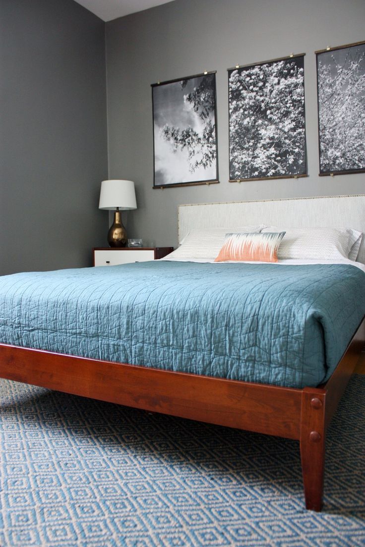 A redwood bed with a white upholstered headboard and white and rich stained wooden nightstands for a chic mid century modern bedroom